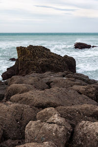 Rock formation on beach against sky