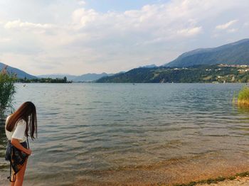 Woman by lake against sky