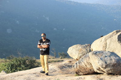 Portrait of man standing on rock against mountain