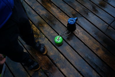 Low section of person standing by containers on wooden floor