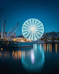 Reflection of illuminated ferris wheel in lake at night