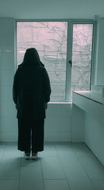 Rear view of woman standing by window
