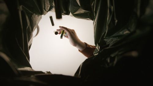 Close-up of human hand behind garbage bags