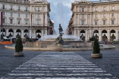 Fountain in front of historic building against sky