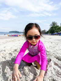Portrait of girl wearing sunglasses on beach against sky