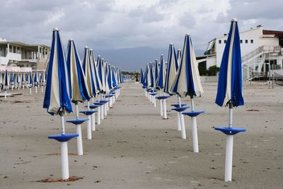 Deck chairs on beach against sky