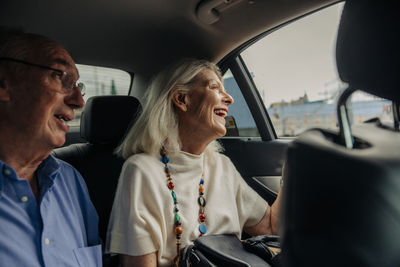 Cheerful senior couple enjoying taxi ride in city