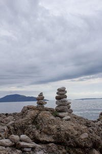 Stack of stones in sea against sky