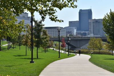 Footpath amidst trees in park against buildings in city. bicentennial park along scioto river