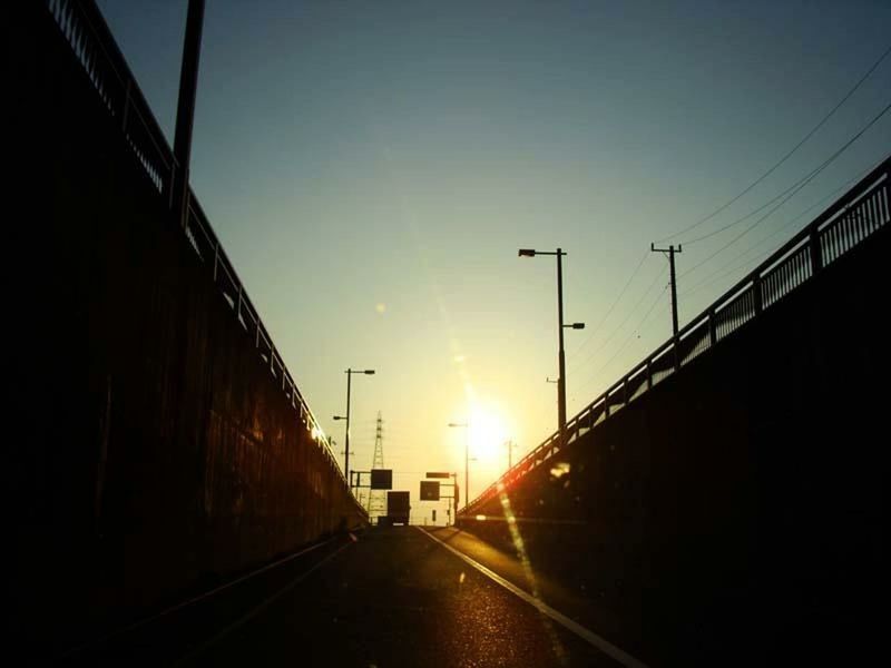transportation, sunset, the way forward, connection, sun, diminishing perspective, built structure, clear sky, vanishing point, architecture, sunlight, road, sky, lens flare, bridge - man made structure, long, sunbeam, silhouette, copy space, electricity pylon