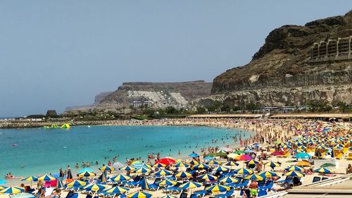 People on beach by sea against clear sky