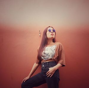 Portrait of young woman standing against wall