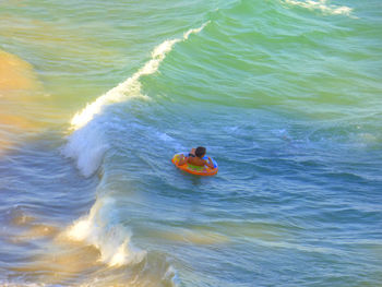 High angle view of shirtless boy floating on inflatable ring at sea