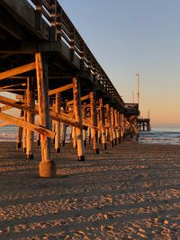 Wooden posts on beach against clear sky during sunset