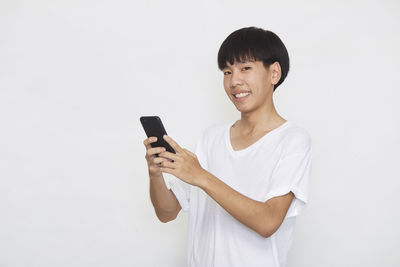 Young man using mobile phone against white background