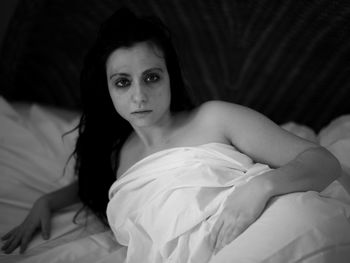 Portrait of topless woman lying on bed