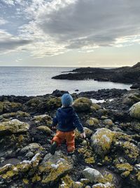 Rear view of man looking at sea against sky