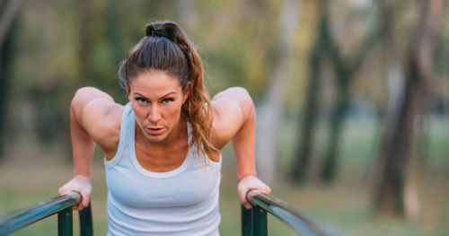Portrait of woman exercising on bars in park