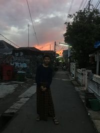 Portrait of man standing on street against sky