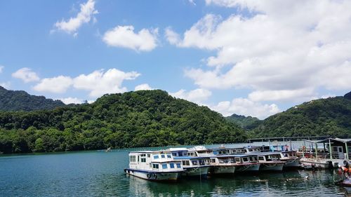 Boat moored on river by trees against sky