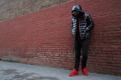 Full length of man standing against brick wall