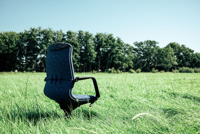 Empty chair on field against clear sky