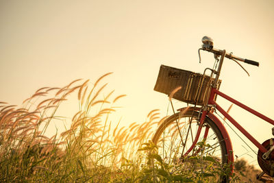 Bicycle on field against sky during sunset