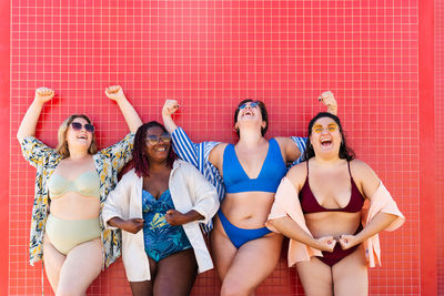 Low angle view of friends standing against wall