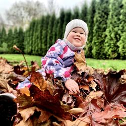 Portrait of smiling boy on leaves during rainy season