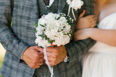 Groom's hands with a bouquet of wedding flowers