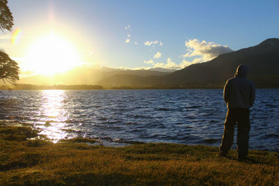 Rear view of man overlooking calm lake