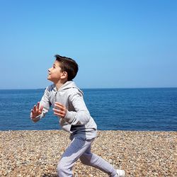 Cute boy playing at beach against clear sky