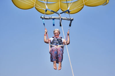 Senior white woman with gray hair is fearless and fun parasailing. extreme sports concept. close up