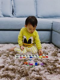 Baby boy playing with toys while sitting on rug at home