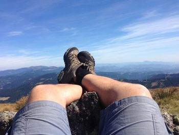 Person standing on rocky mountain against sky