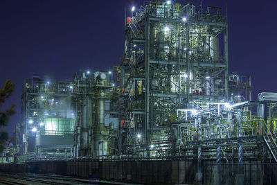 Low angle view of illuminated factory against sky at night