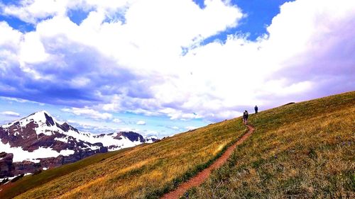 Rear view of man walking on mountain against sky