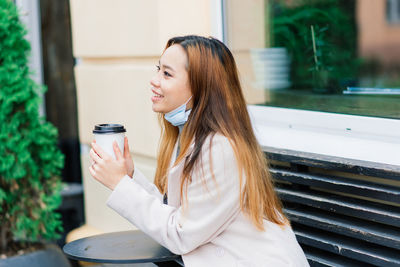 Young woman looking down while sitting outdoors