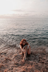 Portrait of young woman in sea against sky