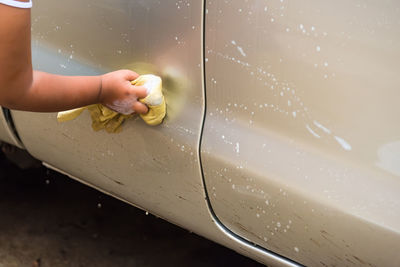 Cropped hand of woman cleaning car