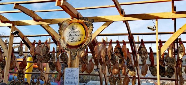 Close-up of fish hanging on wood against sky