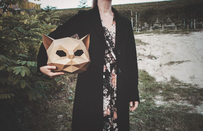 Woman holding a card board cat mask