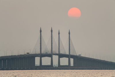 Suspension bridge over river against sky