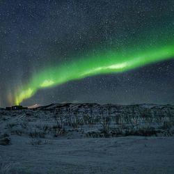 Scenic view of illuminated snowcapped mountains against sky at night