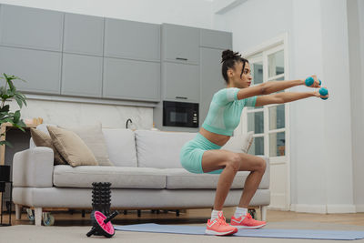 Full length of young woman exercising at home