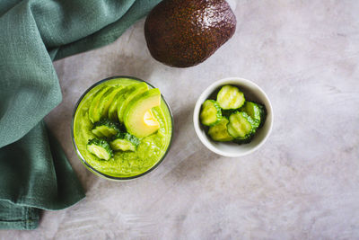 Green smoothie from avocado and cucumbers in a glass on the table top view