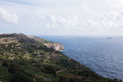 Scenic view of sea and cliff against sky