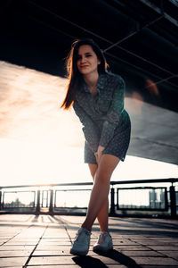 Beautiful young woman standing on railing