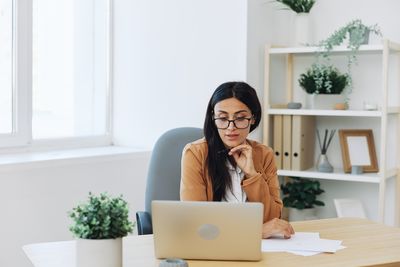 Portrait of young woman using laptop at home