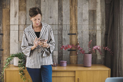 Businesswoman using smart phone against wood paneling in portable office truck